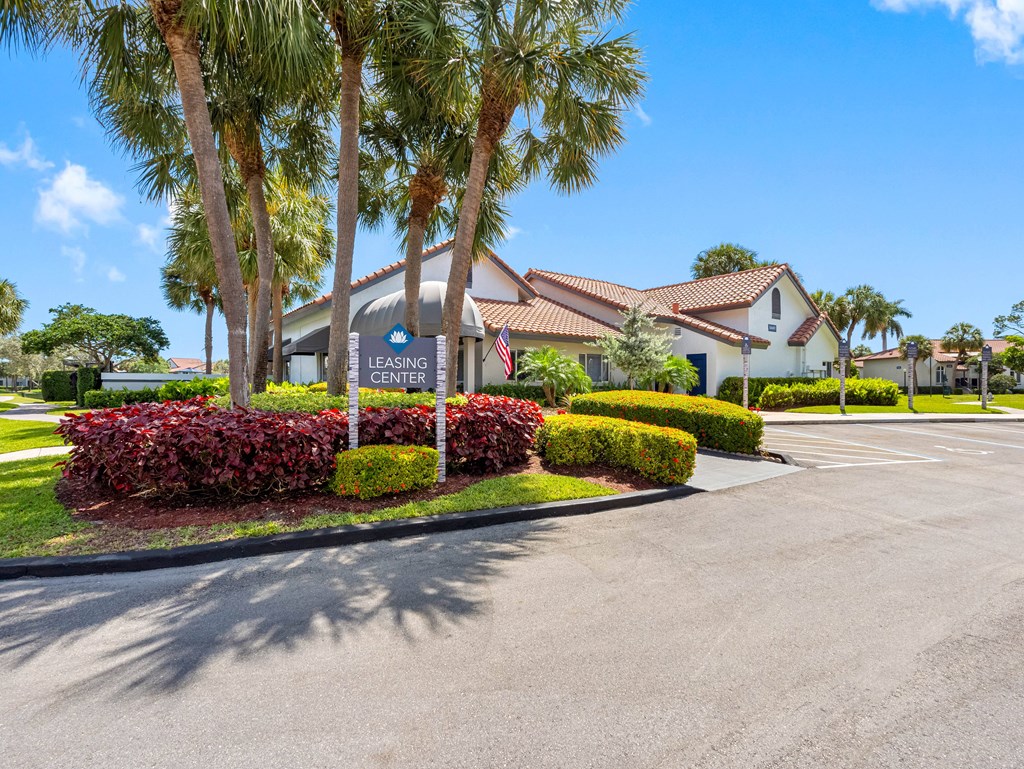 A Leasing Center is surrounded by palm trees and red bushes.